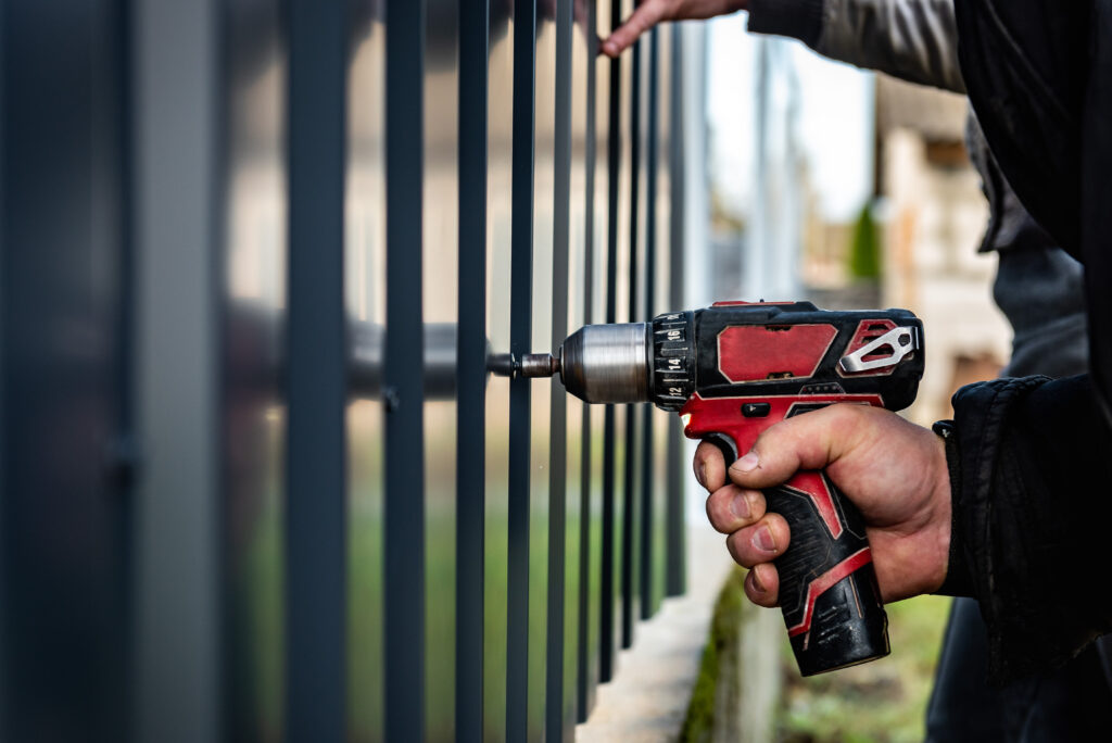 A man installing a residential metal fence.
